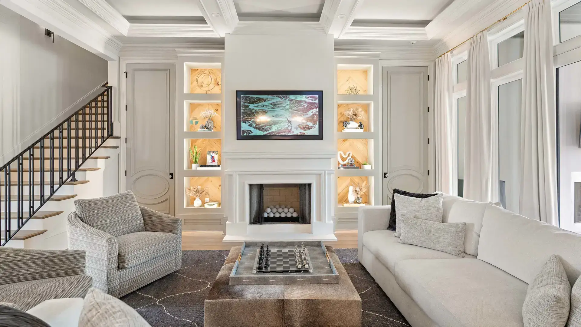 Living room with coffered ceiling, lit display niches and custom millwork in a Troyer Builders luxury home