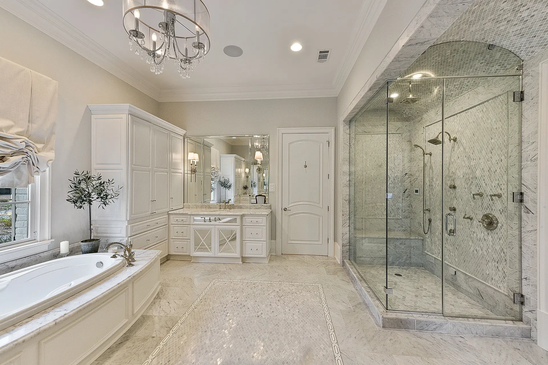 Luxury primary bath with marble details and custom glass shower by Troyer Builders